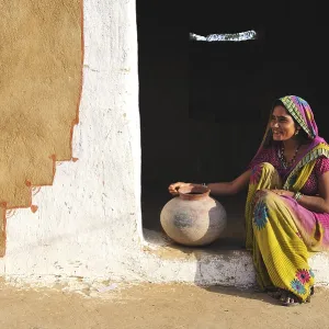 Young woman with water jug at the entrance to her house Young woman with water jug at the entrance to her house