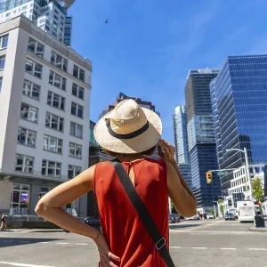 Young woman wearing a straw hat enjoying the cityscape of vancouver