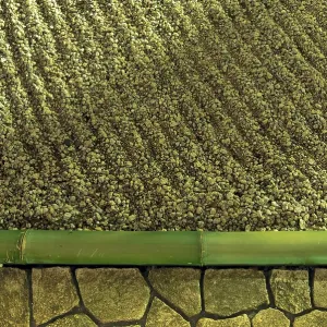 Zen stone garden fragment under vivid night illumination with sand waves and bamboo pole border