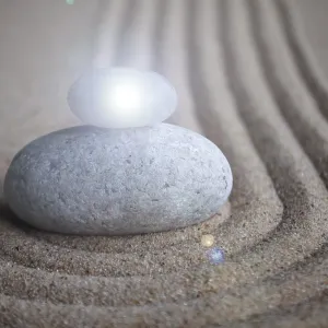 Zen stones with shining light on sand with customizable space for text or message