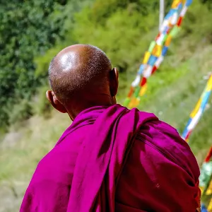 ZHANGYE, CHINA - JUNE 26: Old buddhist monk looking at colorful praying flags by Mati Si cave temple near Zhangye ZHANGYE, CHINA - JUNE 26: Old buddhist monk looking at colorful praying flags by Mati Si cave temple near Zhangye