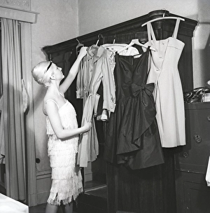 1920s clothes. A woman in the 1960s with a feel for 1920s fashion has selected different outfits on hangers from her wardrobe to wear. Sweden 1962. Kristoffersson ref CS101-10