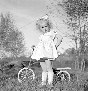 In the 1940s. A blonde little girl in a nice dress on her tricycle