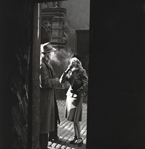 1940s couple. A couple pictured in the evening sun in an old street smoking a cigarette