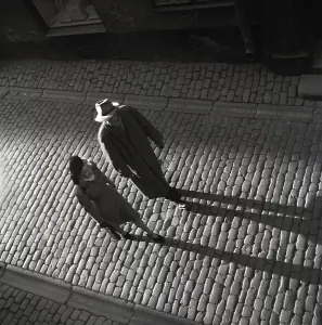 1940s couple. The man and woman walking in an old street cast long shadows when the evening sun shines on them