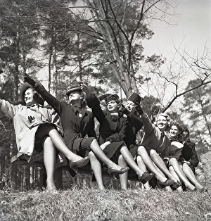 In the 1940s. A group of young people sitting together all points in one direction with their arms as if they want to