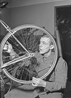 1940s man with bicycle. The Swedish athlete and olympic skating champion Ake Seyffarth is repairing a bicycle and wheel