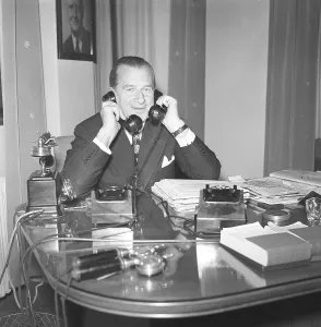 In the 1940s. A man in an office with two telephones looking busy