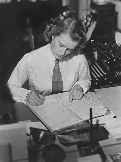 1940s office clerk. A young woman in an office where she make careful notes in a registrer
