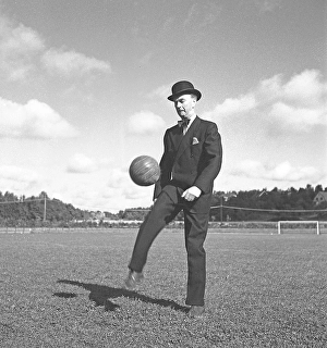 1940s soccer player. A gentleman dressed in a suit and a bowler hat is kicking a football in the air