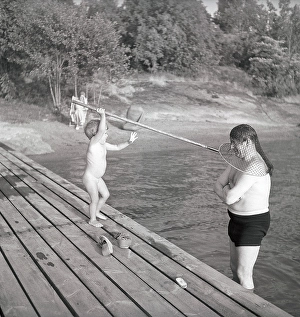 1940s summer. A man and father is standing caught by his daughter in a fishing net