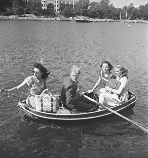 1940s summer. Four people are sitting in a very small rowing boat