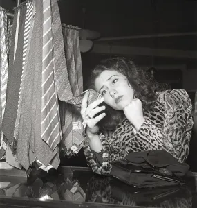 1940s woman. She is looking to buy her husband or boyfriend a gift and is having a hard time selecting the necktie among the selection in front of her. She looks at one but does not seem really happy about choosing this one. Sweden 1945 ref L60-6