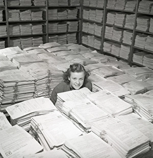 1940s working girl. A young woman in the storage room of thousands and thousands of documents
