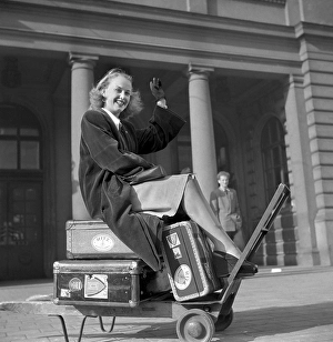 In the 1940s. A young woman photographed sitting on her luggage