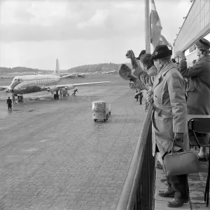 1950s airport. People are standing on an outdoor terrace overviewing the aircrafts waving goodbye to someone