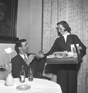 In the 1950s. A cigarette girl going around the tables in the restautrant selling cigarettes from her box seen in front