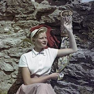 1950s fashion. A young woman is wearing a white blouse and a matching hat