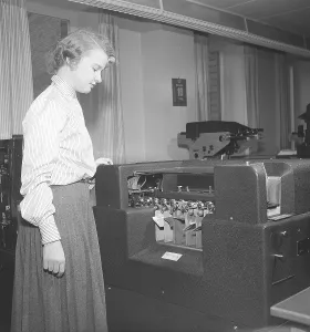 In the 1950s. A female clerk at punch card reader machine overlooking it's function