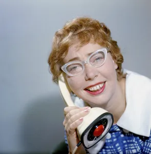 1950s glasses and telephone. A young woman in typical fifties glasses and bows is talking on the telephone