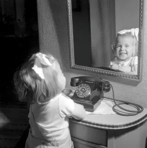In the 1950s. A little girl pictured by a telephone