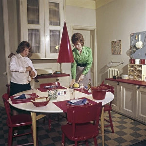 In the 1950s. A lovely color picture of two teenage girls setting the table with plates