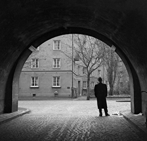 In the 1950s. A man in full figure stands in the street at the edge of a tunnel