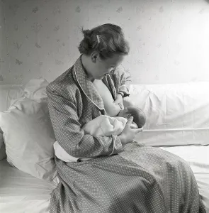 1950s mother nursing her baby. A young woman breastfeeding her baby at home