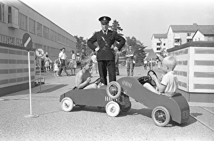 1950s policeman. Two boys are playing in their pedal cars