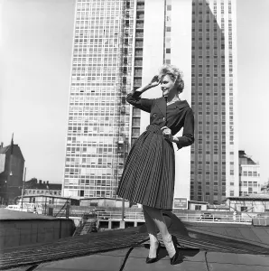 In the 1950s. A woman modelling a 1950s outfit with a jacket and skirt in matching dark