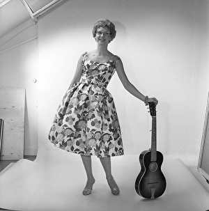 In the 1950s. A woman in the photographers studio wearing a dress patterned with flowers and leaves