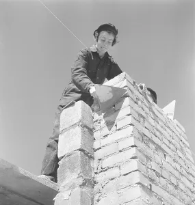 In the 1950s. Women construction worker is laying bricks on a building site