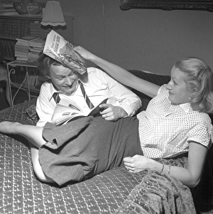 In the 1950s. A young couple at home is seen fighting in a playful manor. She hits him over the head with a book. 1952. Conard ref 2251