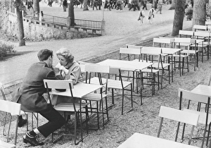 In the 1950s. A young couples sits on an outdoor cafe sharing a soda
