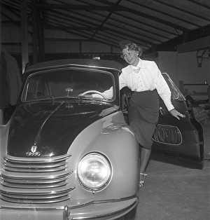In the 1950s. A young woman on the hood of the brand new car