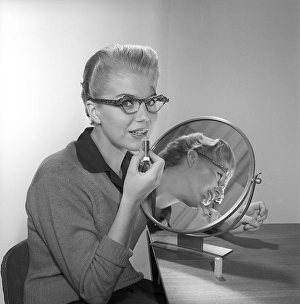 In the 1950s. A young woman with a mirror putting lipstick