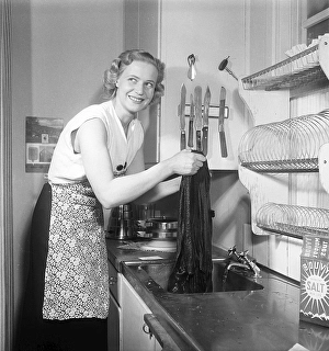 This is how it was done in the 1950s. A young woman stands at the kitchen sink and uses Bouvy salt with iodine to dye or wash her clothes. She rinses with clean water and looks pleased with the result. 1951. Kristoffersson ref BB68-1