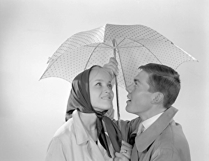 1960s couple. A happy smiling couple is standing under an umbrella