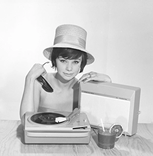 1960s lifestyle. A young woman with a Philips radio and a gramophone as it could look in the summer. The summer hat, sun glasses and the cool drink glass is in the picture is added to get the right summer feeling in the studio