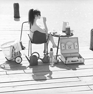 1960s lifestyle. A young woman sitting in the sun wearing a bikini