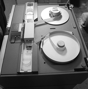 In the 1960s. A unit within a IBM system 360 and a punched tape reader in detail. The information that the punched holes represented was read and transferred further in the system to a storage media, a program, a tape unit