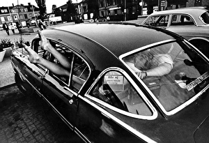 In the 1960s. A vintage american car parked in a square in a small town in Sweden. A typical 1960s youth motor culture of cruising, driving and having fun together often at night. Sweden 1964