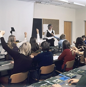 In the 1970s. A school class sits in the benches during a lesson with a female teacher