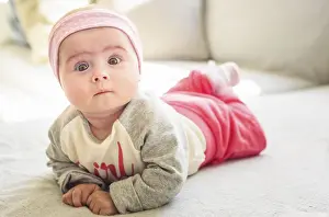 6 months old baby girl lie on a couch in bright sunny living room