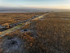From above, image of military vehicles parked along a rural road impacted by the war through a vast