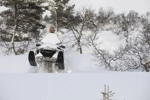 Adult man playing and jumping with a snowmobile in the snow on the mountain in Norway