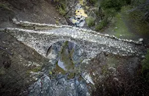 Aerial drone photograph of a medieval stoned bridge with water flowing in the river