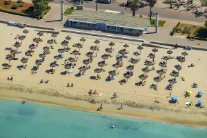 Aerial view, beach life and sunbathing with straw parasols