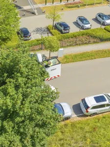 Aerial view of a car park next to a road with trees