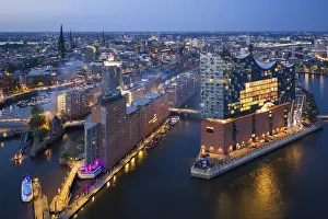 Aerial view of the Elbphilharmonie at blue hour with illuminated windows and view over the Speicherstadt and Hafencity